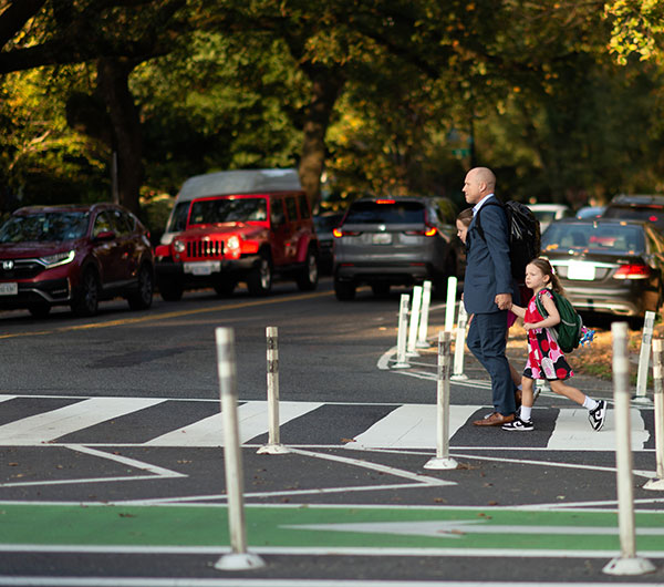 father and daughter walking across a crosswalk