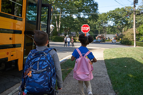 two children getting on a school bus.