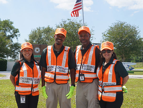 four crossing guards standing together with safety vests on.