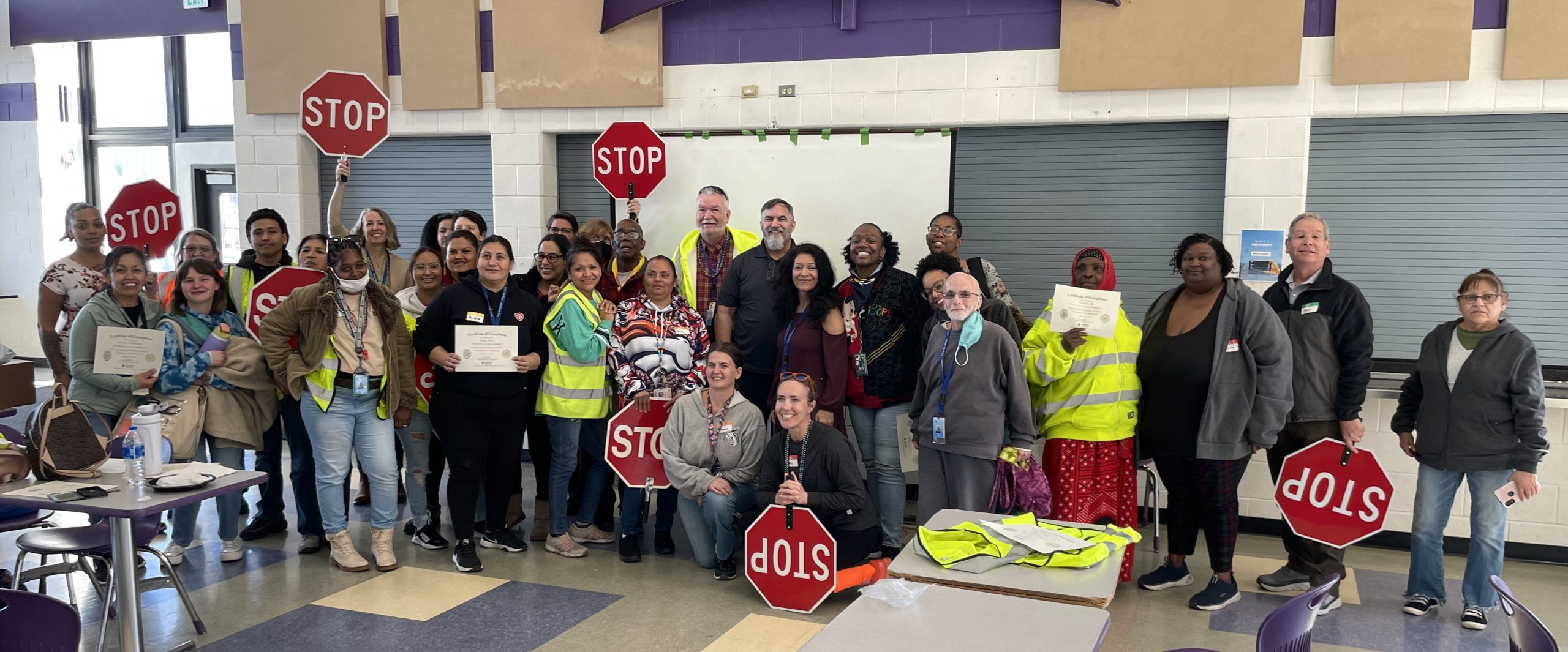 large group of crossing guards holding up stop signs in a cafeteria